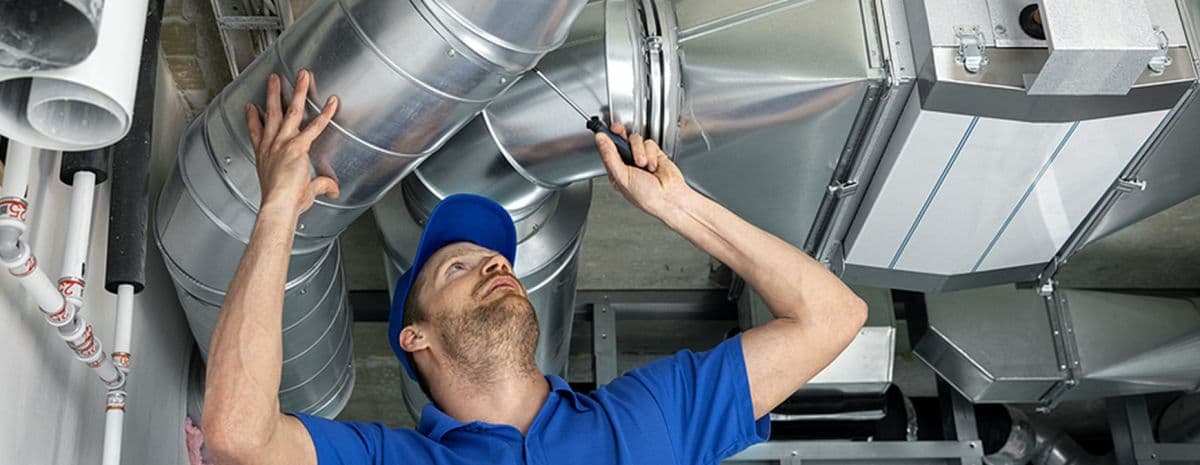 Technician inspecting and repairing ductwork